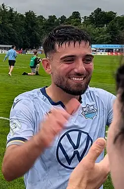 Player smiling as he approaches a fan to shake his hand