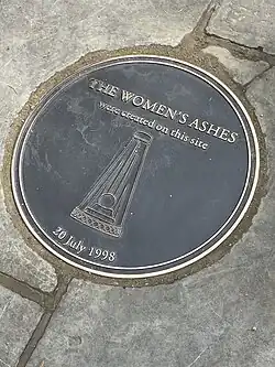 A metal plaque set in flagstones with a pyramid shaped trophy and the date 20 July 1998.