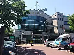 A photograph of a multi-story building, taken from its parking lot.