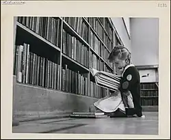 Young girl reading a book, Central Circulating Library at College and St. George Streets, Toronto, Ontario, c. 1930–1960.