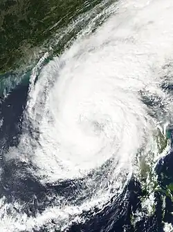 A satellite photograph of a weakening tropical cyclone east of Luzon. Its circulation is partially-exposed and convection is limited to the north and south, though the storm has excellent outflow indicated by a broad area of high clouds to the northeast.