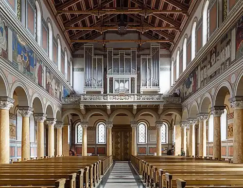 Interior of the church, facing west, showing the murals and the Kuhn organ